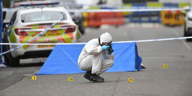 A police forensics officer taking photographs in Irving Street, in Birmingham after a number of people were stabbed in the city centre on Sunday. (Jacob King/PA via AP)