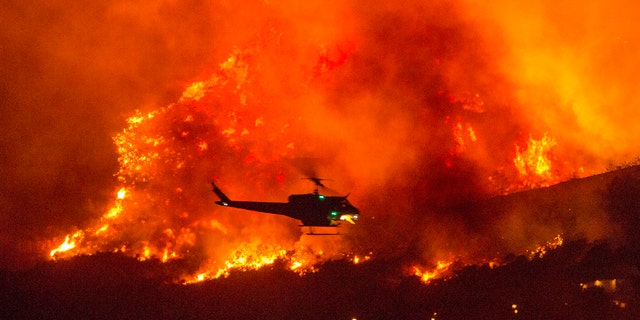 In this Saturday, Sept. 5, 2020, file photo, a helicopter prepares to drop water at a wildfire in Yucaipa, Calif.