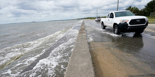 Waters from the Guld of Mexico poor onto a local road, Monday, Sept. 14, 2020, in Waveland, Miss.