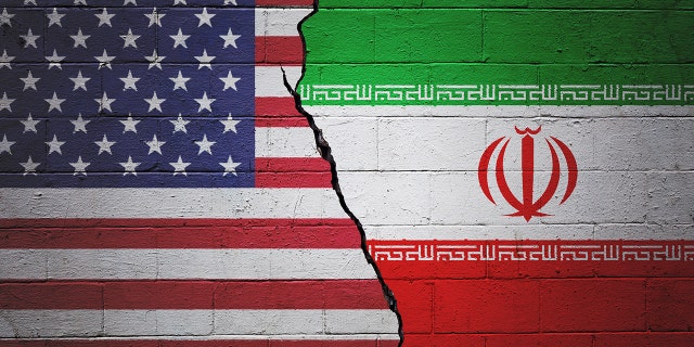 A cracked brick wall painted with an American flag on the left and an Iranian flag on the right.