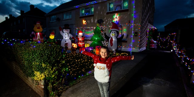 Theo Gabe, 5, outside of his home in Wales, which mom Caroline has decorated with 3,000 Christmas lights, sparkling snow and oversized, inflatable yuletide characters.