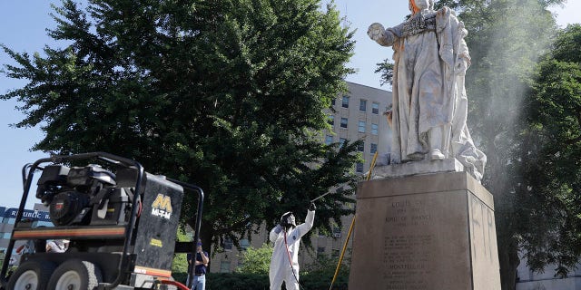 In this June 2, 2020 file photo, a worker cleans the King Louis XVI statue in Louisville, Ky., after it was hit with paintballs during a protest the previous evening. (AP Photo/Darron Cummings)