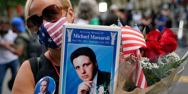 Diane Massaroli holds flowers flags and photo of her husband Michael Massaroli who died during the Sept. 11, 2001 attacks at the World Trade Center, before a ceremony organized by the Tunnel to Towers Foundation, in New York. (AP Photo/Mark Lennihan) (AP Photo/Mark Lennihan)