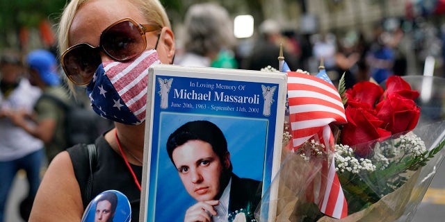Diane Massaroli holds flowers flags and photo of her husband Michael Massaroli who died during the Sept. 11, 2001 attacks at the World Trade Center, before a ceremony organized by the Tunnel to Towers Foundation, in New York. (AP Photo/Mark Lennihan) (AP Photo/Mark Lennihan)
