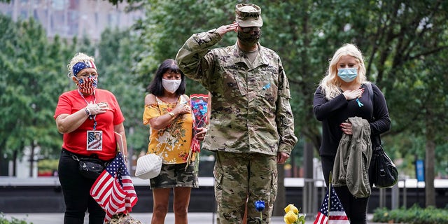 US Army Sgt. Edwin Morales, center right, salutes after places flowers for fallen FDNY firefighter Ruben D. Correa at the National September 11 Memorial and Museum, Friday, Sept. 11, 2020, in New York. (AP Photo/John Minchillo)