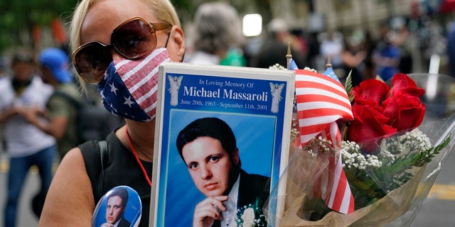 Diane Massaroli holds flowers, flags and a photo of her husband Michael Massaroli who died during the Sept. 11, 2001, attacks at the World Trade Center. (AP Photo/Mark Lennihan)