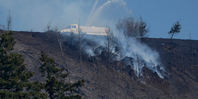 A tanker truck sprays water on a persistent hotspot of a wildfire on a ridge, Wednesday, Sept. 9, 2020, near Bonney Lake, Wash., south of Seattle.