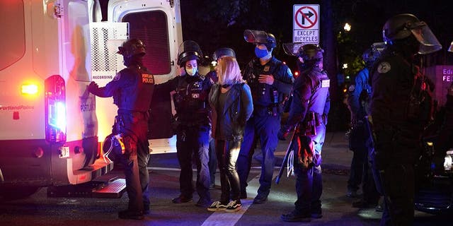 A female protester is loaded into a van after being arrested while rallying at the Mark O. Hatfield United States Courthouse on Saturday, Sept. 26, 2020, in Portland, Ore. (Associated Press)