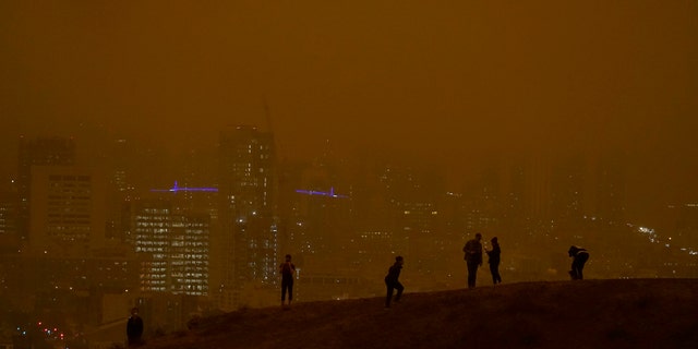 People look toward the skyline obscured by wildfire smoke during daytime from Kite Hill Open Space in San Francisco, Wednesday, Sept. 9, 2020.