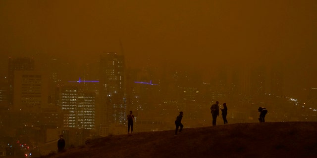People look toward the skyline obscured by wildfire smoke during daytime from Kite Hill Open Space in San Francisco, Wednesday, Sept. 9, 2020.