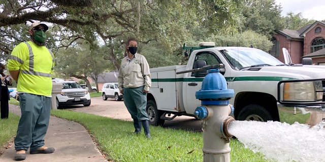 City workers Kristina Watson, right, and Lennie Miner, a maintenance foreman monitor Monday, Sept. 28, 2020, test water flowing out of a hydrant in Lake Jackson, Texas. 
