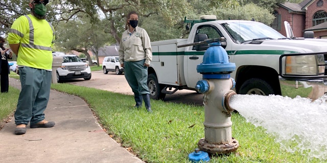 City workers Kristina Watson, right, and Lennie Miner, a maintenance foreman monitor Monday, Sept. 28, 2020, test water flowing out of a hydrant in Lake Jackson, Texas.