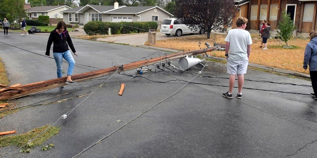 Residents look at a downed power pole that was blown over in high winds on Tuesday, Sept. 8, 2020, in Hyrum, Utah.