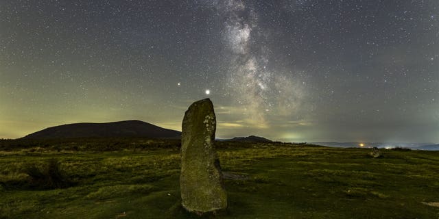 A dramatic night sky aligns with the center stone of the Mitchell's Fold stone circle in southwest Shropshire, September 27, 2020. (Credit: SWNS)