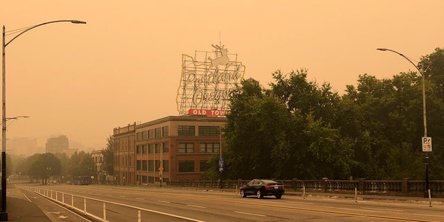 The Portland Oregon Old Town sign is seen under heavy smoke from the wildfires creating an orange glow over Portland, Ore., Saturday, Sept. 12, 2020.