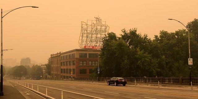 The Portland Oregon Old Town sign is seen under heavy smoke from the wildfires creating an orange glow over Portland, Ore., Saturday, Sept. 12, 2020.