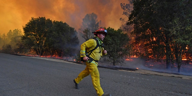 A firefighter runs to his firetruck while protecting a home along Crystal Springs Road while battling the Glass Fire in St. Helena, Calif., on Sunday, Sept. 27, 2020.