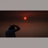 Jason Anderson, 42, takes pictures as the sun is visible through thick smoke generated by the Bobcat Fire in San Dimas, Calif., Wednesday, Sept. 9, 2020. Hazy clouds of smoke from dozens of wildfires darkened the sky to an eerie orange glow over much of the West Coast on Wednesday, keeping street lights illuminated during the day and putting residents on edge.