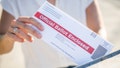 A young woman places her absentee voter ballot for the 2020 presidential election into a blue United States Postal mailbox.