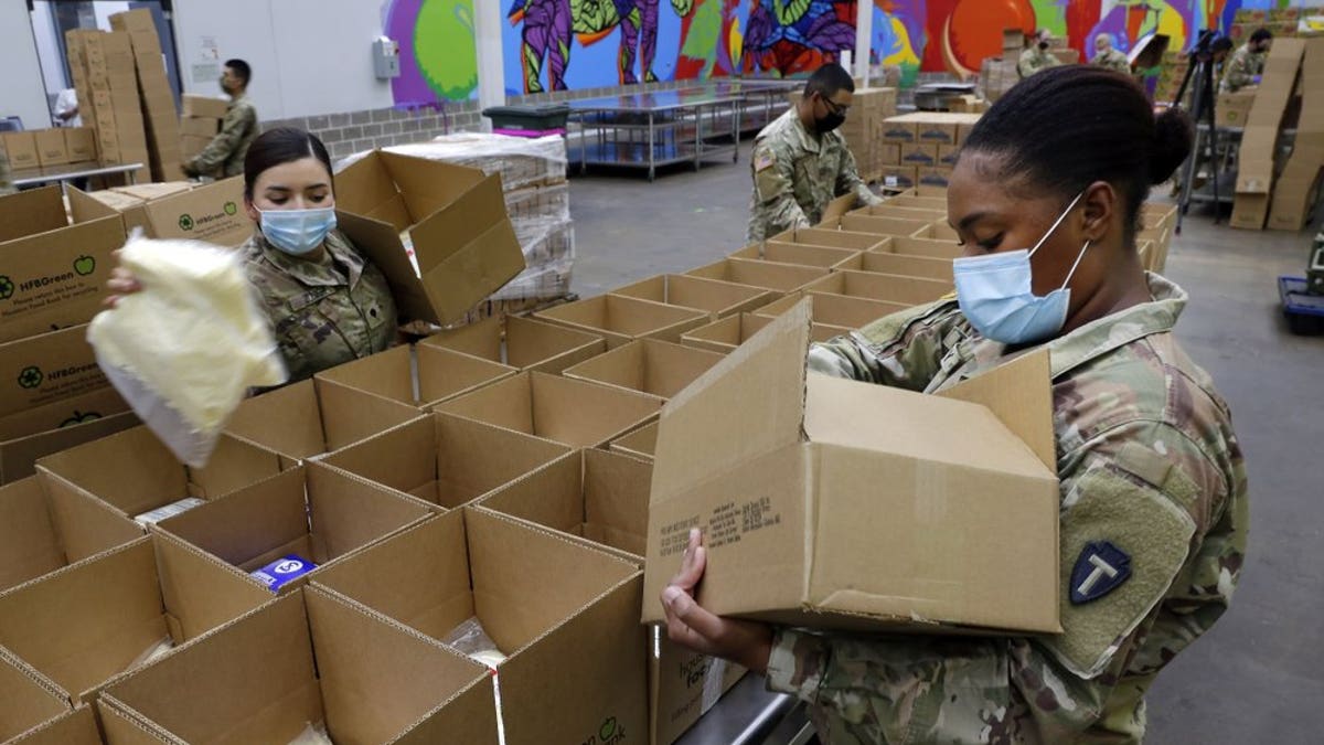 Texas National Guard soldiers Spc. Esmeralda Zuniga, left, and Spc. Samantha McClasky, right, load boxes with various dairy products such as milk, cheese and butter, at the Houston Food Bank Wednesday, Oct. 14, 2020, in Houston. When the pandemic hit last March, the volunteer count at the food bank dropped 80 percent. The Guard stepped in to fill the gap and has been assisting ever since. (AP Photo/Michael Wyke)