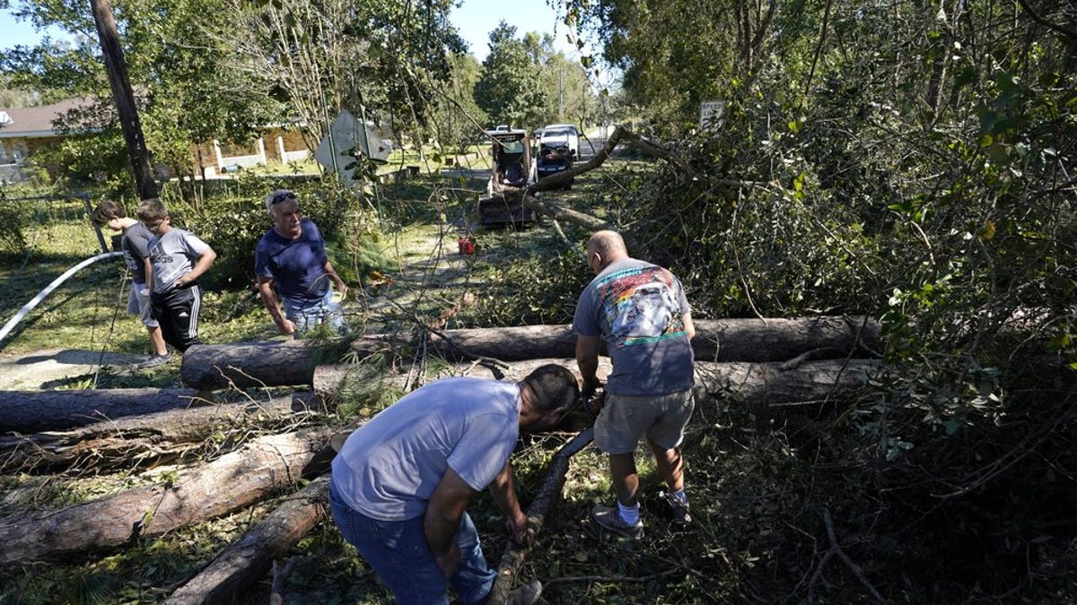 Residents use chain saws to clear fallen trees in the aftermath of Hurricane Zeta in Waveland, Miss., Thursday, Oct. 29, 2020. (AP Photo/Gerald Herbert)