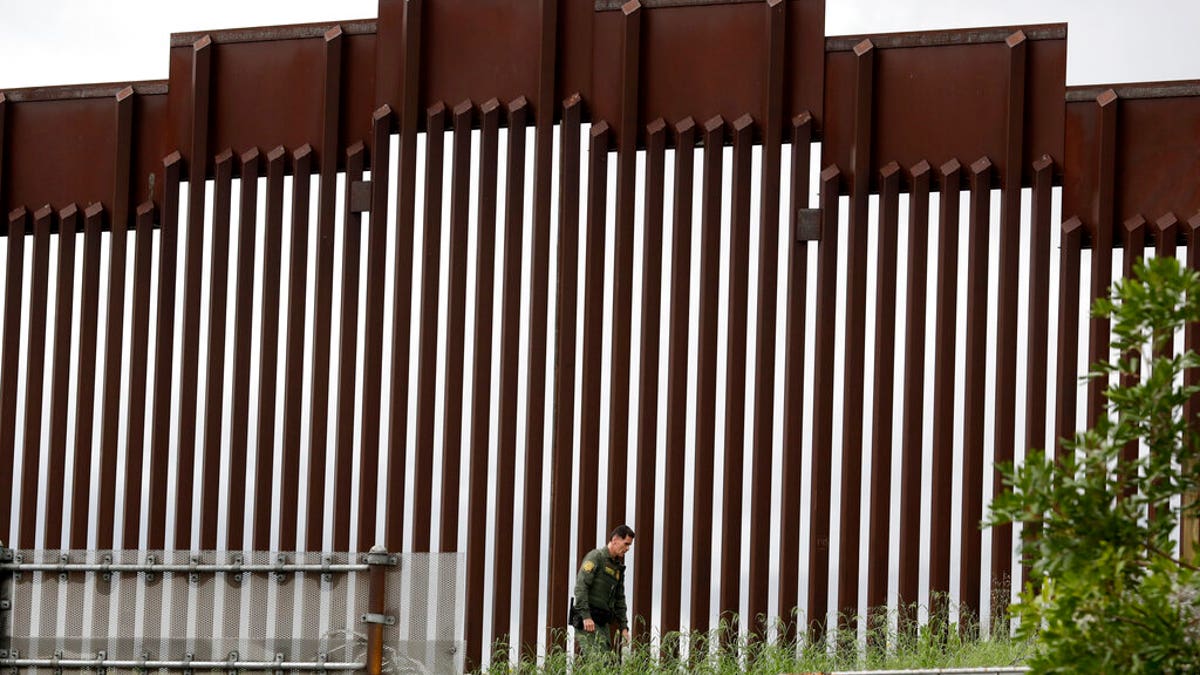 FILE - In this March 18, 2020, file photo, a Border Patrol agent walks along a border wall separating Tijuana, Mexico, from San Diego, in San Diego. Vice President Mike Pence in March directed the nation’s top disease control agency to use its emergency powers to effectively seal the U.S. borders, overruling the agency’s scientists who said there was no evidence the action would slow the coronavirus, according to two former health officials. (AP Photo/Gregory Bull, File)