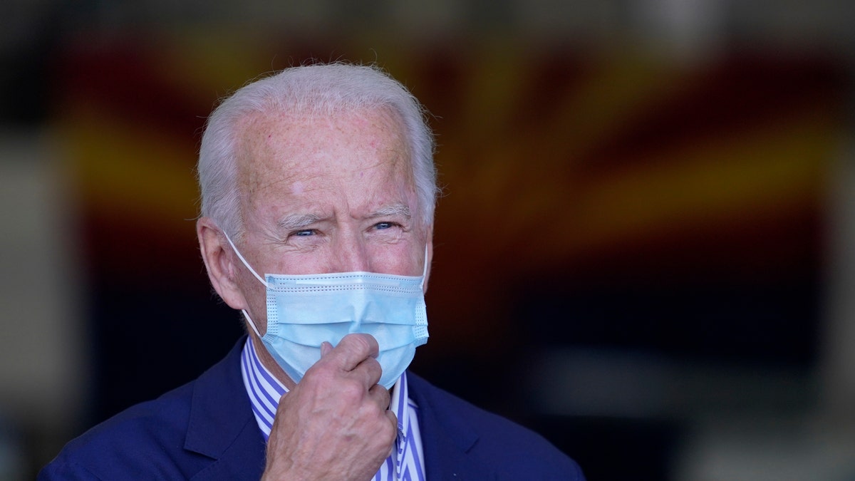 With the Arizona state flag in the background, Democratic presidential candidate former Vice President Joe Biden speaks to members of the media before leaving Phoenix Sky Harbor International Airport, in Phoenix, Thursday, Oct. 8, 2020. (AP Photo/Carolyn Kaster)