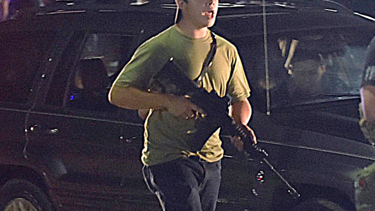 In this Tuesday, Aug. 25, 2020, file photo, Kyle Rittenhouse carries a weapon as he walks along Sheridan Road in Kenosha, Wis., during a night of unrest following the weekend police shooting of Jacob Blake. In a document filed Thursday, Oct. 8, 2020, defense attorneys say sending Rittenhouse, who is accused of killing two protesters days after Jacob Blake was shot by police in Kenosha, Wis., to stand trial in Wisconsin would 'turn him over to the mob.' (Adam Rogan/The Journal Times via AP, File)