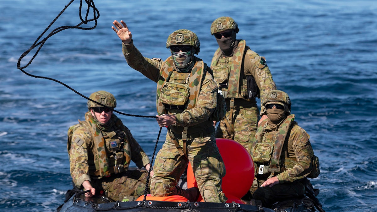 In this Sept. 25, 2020, photo provided by the Royal Australian Navy, members of the Australian Clearance Diving Team One return to Lord Howe Island, Australia, from Elizabeth Reef on a Zodiac inflatable boat following a successful search for unexploded ordnance. The 45-kilogram (100-pound) bomb was found by a fisherman on Elizabeth Reef near Lord Howe Island, about 550 kilometers (340 miles) off New South Wales state. (ABIS Sittichai Sakonpoonpol/Royal Australian Navy via AP)