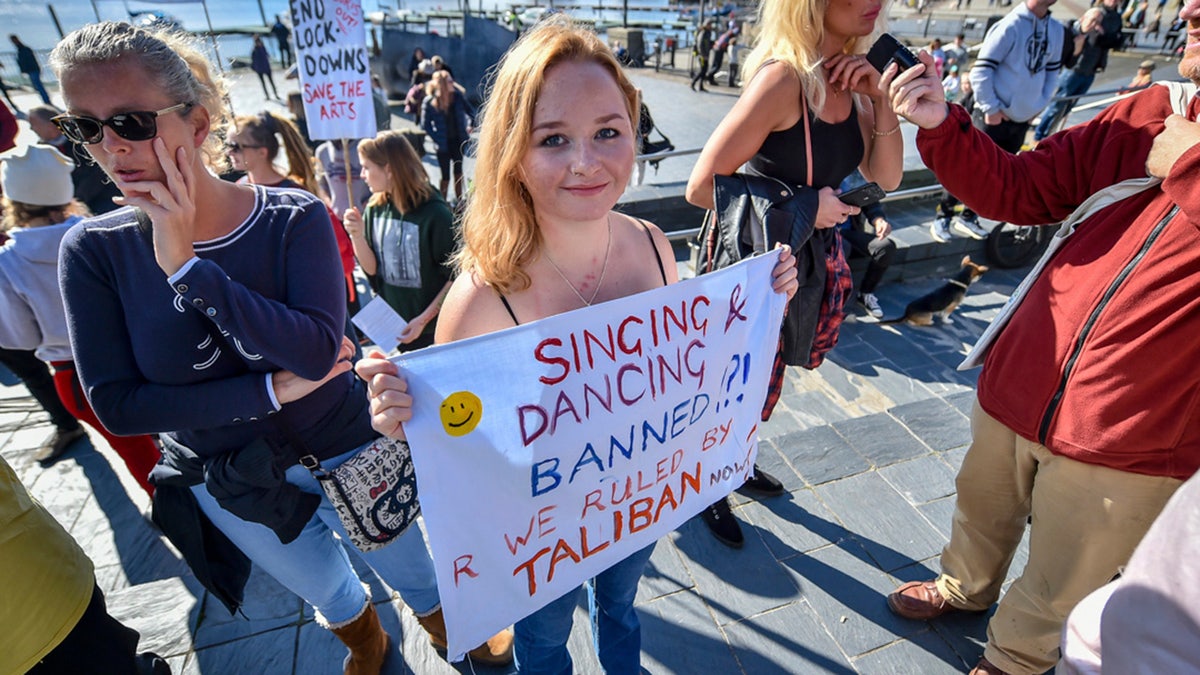 A woman holds a banner during an anti-lockdown protest outside the Senedd Cymru in Cardiff Bay, Wales, Sunday, Oct. 11, 2020. So far the U.K. has experienced Europe’s deadliest virus outbreak, with over 42,750 confirmed deaths. (Ben Birchall/PA via AP)
