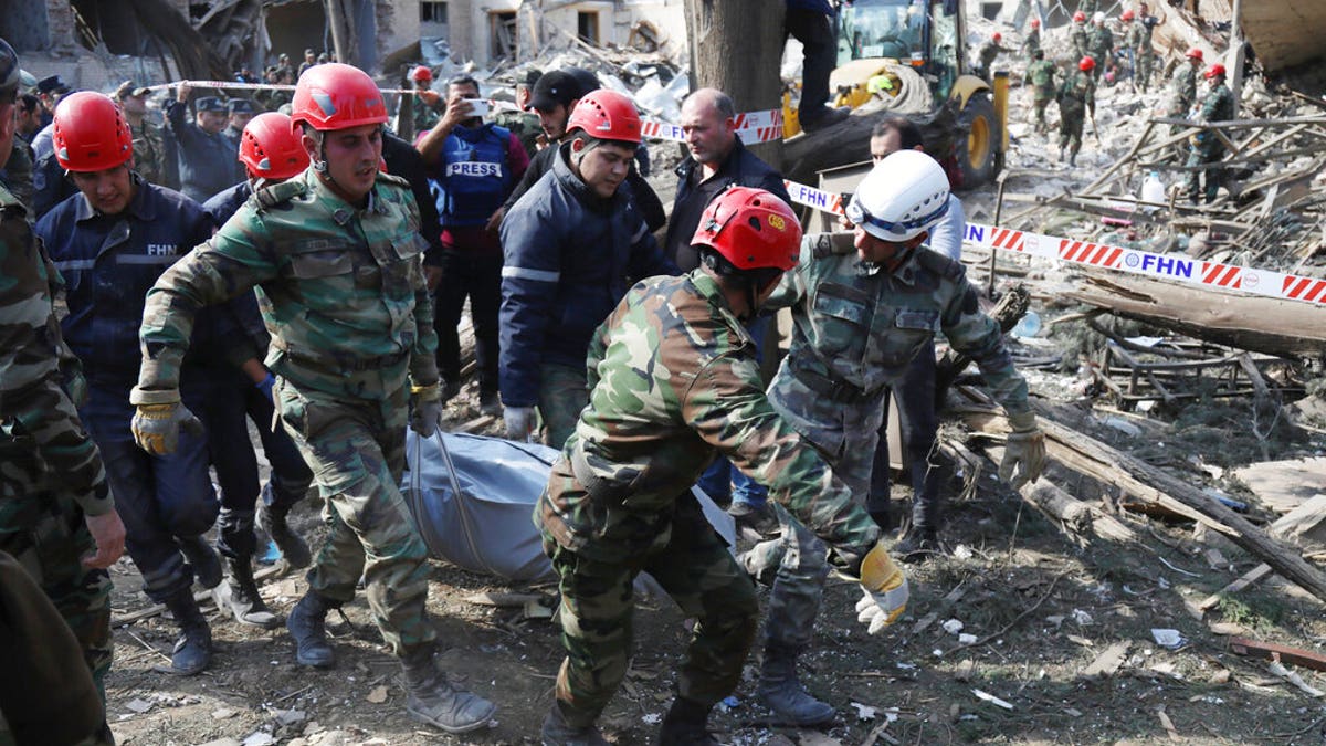 FILE - In this Oct. 11, 2020, file photo, rescuers carry an injured person to an ambulance after shelling by Armenian artillery during fighting in Ganja, Azerbaijan. (AP Photo/Aziz Karimov, File)