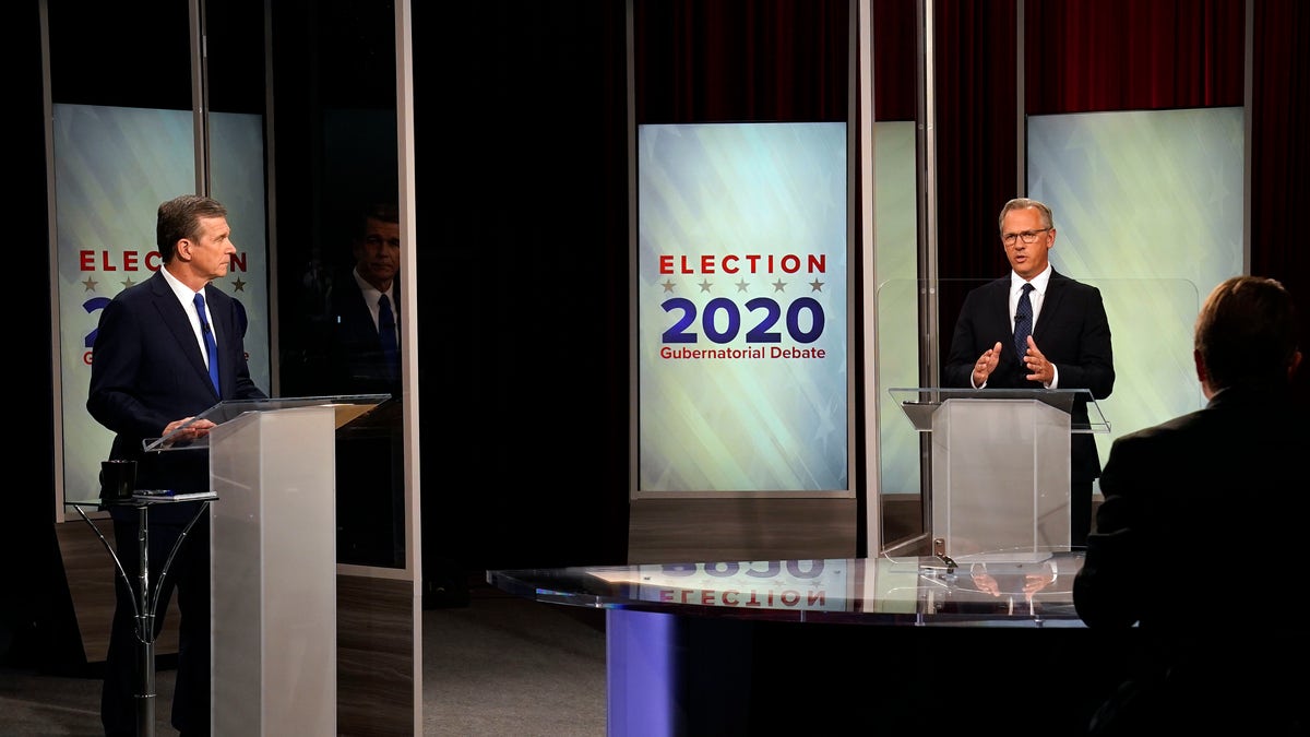 North Carolina Gov. Roy Cooper, left, and Lt. Gov. Dan Forest participate in a live televised debate moderated by Wes Goforth at UNC-TV studios in Research Triangle Park, N.C., Wednesday, Oct. 14, 2020. (AP Photo/Gerry Broome)