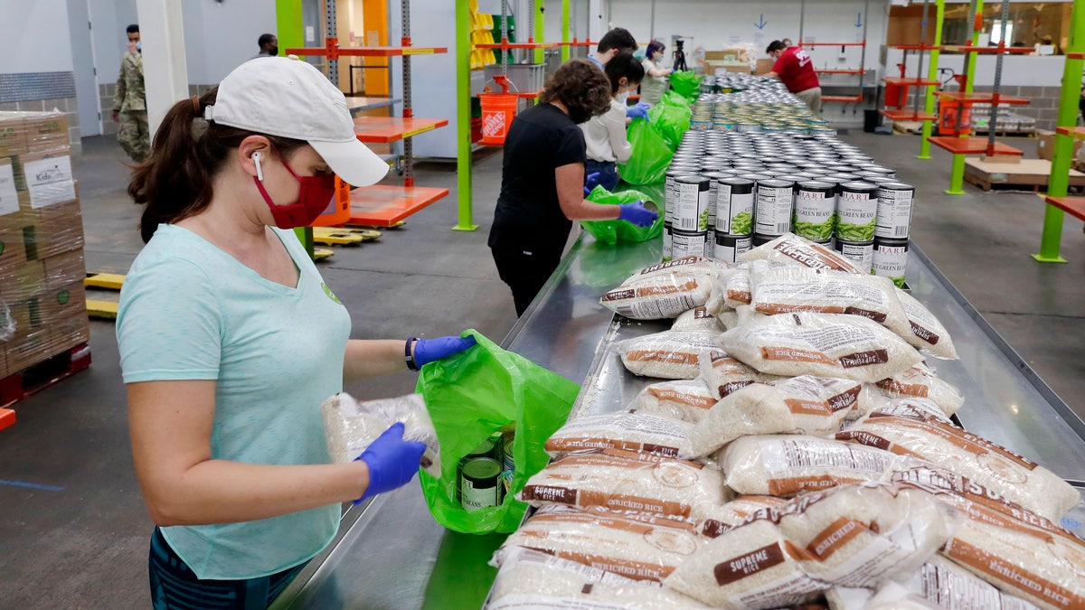 Volunteers load non-perishable foods into green grocery bags for distribution to a local school's food program. (AP Photo/Michael Wyke)