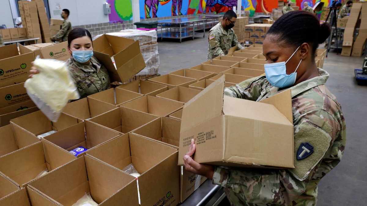 Texas National Guard soldiers Spc. Esmeralda Zuniga, left, and Spc. Samantha McClasky, right, load boxes with various dairy products at the Houston Food Bank on Oct. 14. (AP Photo/Michael Wyke)