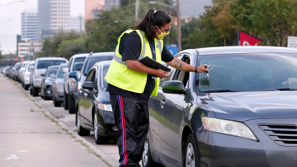 Volunteer Sharely Gomez marks the windshield after taking information from clients in their cars as they wait in line at West Houston Assistance Ministries. (AP Photo/Michael Wyke)