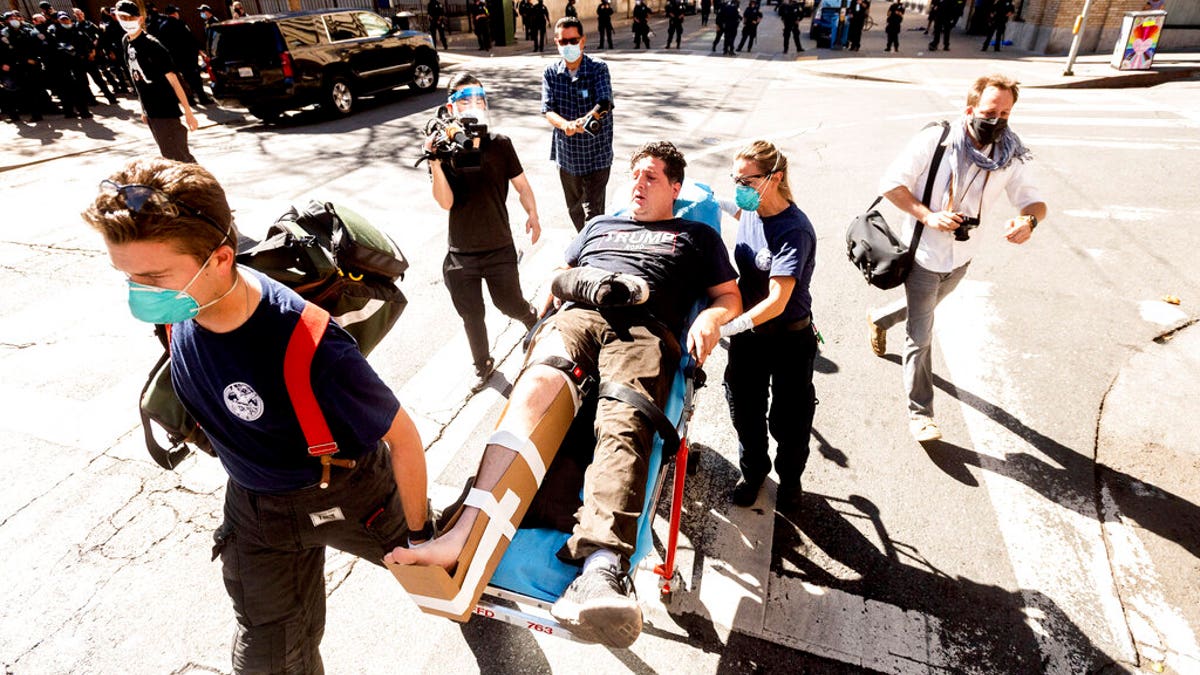 Medics transport a supporter of President Donald Trump to an ambulance after he was attacked by counter-protesters in San Francisco on Saturday, Oct. 17, 2020. About a dozen pro-Trump demonstrators were met by several hundred counter-protesters as they tried to rally. (AP Photo/Noah Berger)