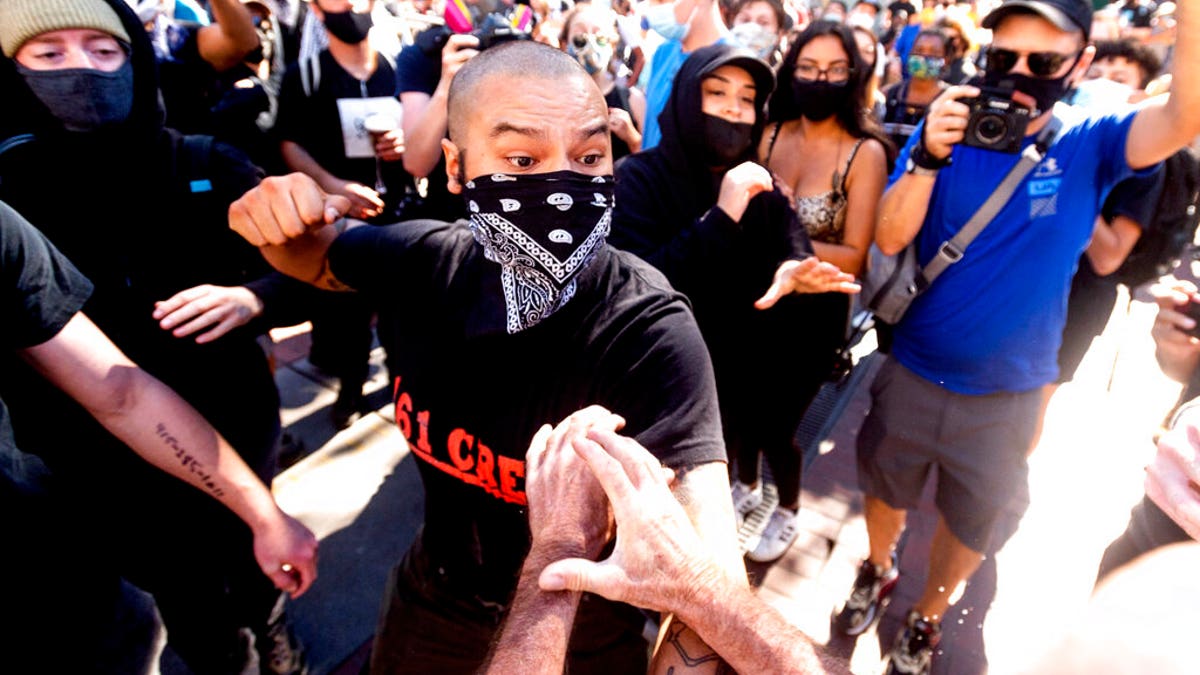 A counter-protester, who declined to give his name, prepares to hit a conservative free speech rally organizer in San Francisco on Saturday, Oct. 17, 2020. About a dozen pro-Trump demonstrators were met by several hundred counter-protesters as they tried to rally. (AP Photo/Noah Berger)