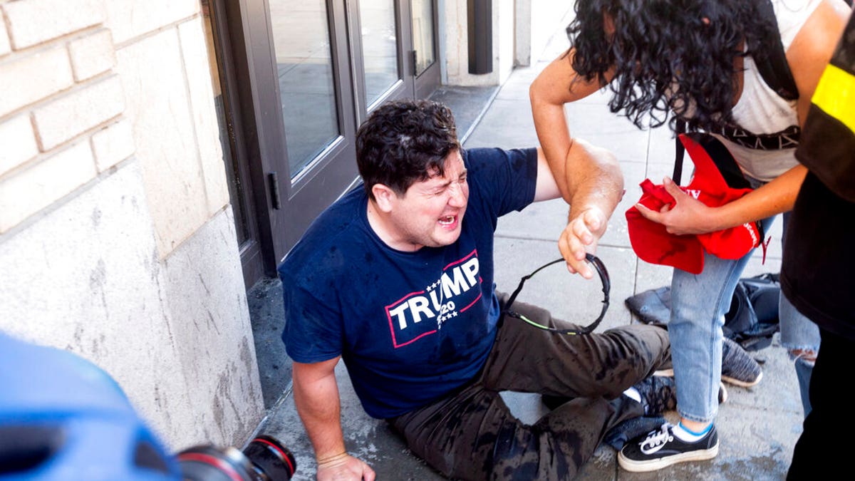 A supporter of President Donald Trump lies on the ground after he was attacked by counterprotesters in San Francisco, Saturday, Oct. 17, 2020. About a dozen pro-Trump demonstrators were met by several hundred counterprotesters as they tried to rally. (AP Photo/Noah Berger)
