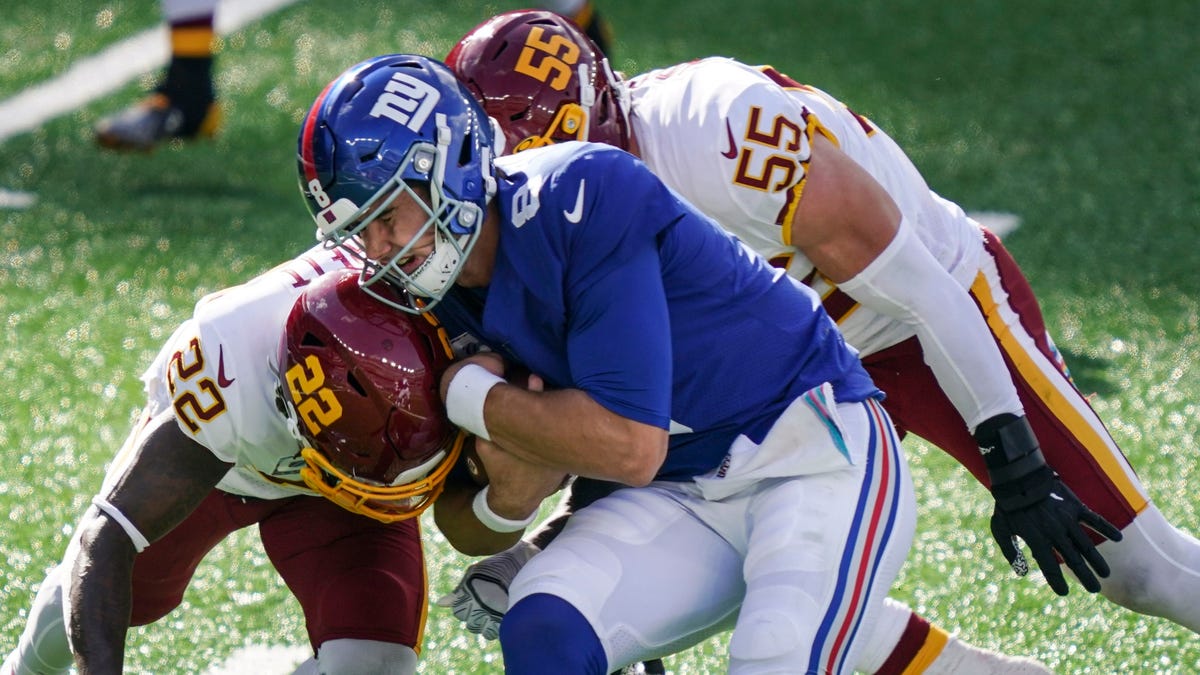 Washington Football Team's Deshazor Everett (22) and Cole Holcomb (55) tackle New York Giants quarterback Daniel Jones (8) during the second half of an NFL football game Sunday, Oct. 18, 2020, in East Rutherford, N.J. (AP Photo/John Minchillo)