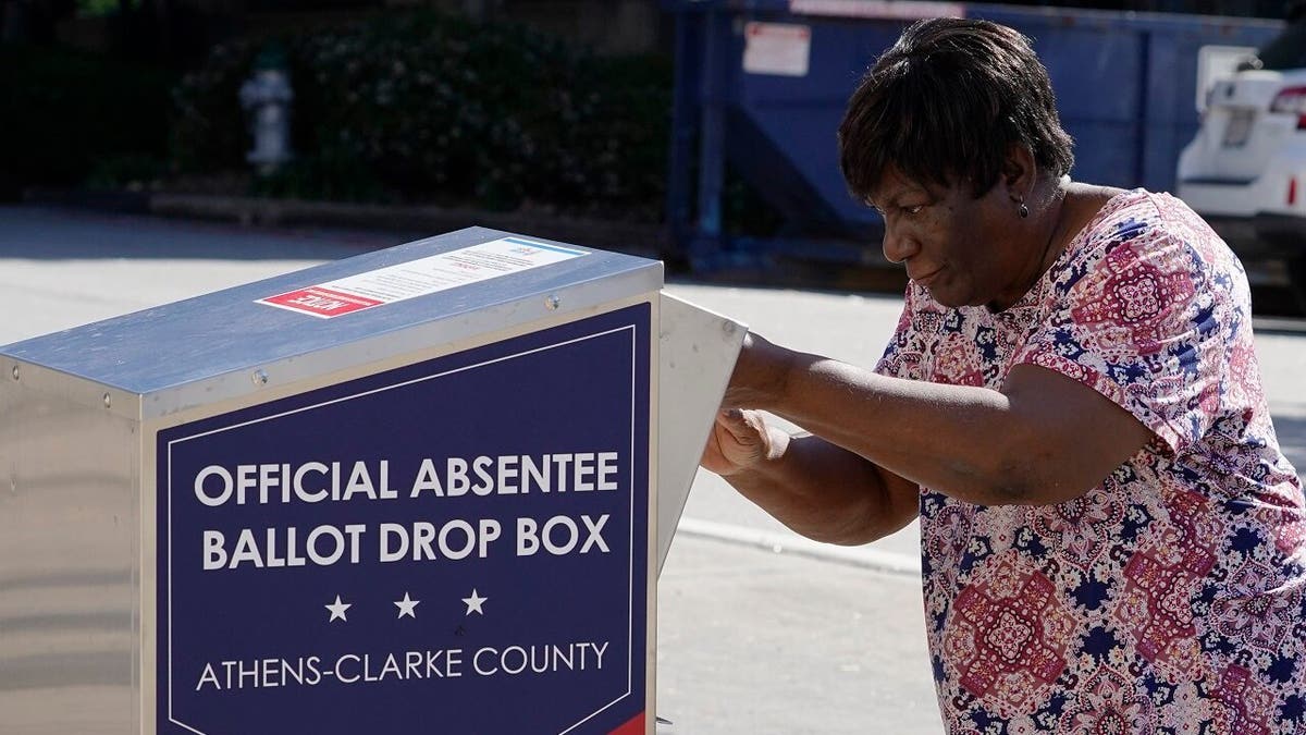 A voter drops their ballot off during early voting, Monday, Oct. 19, 2020, in Athens, Ga. (AP Photo/John Bazemore)