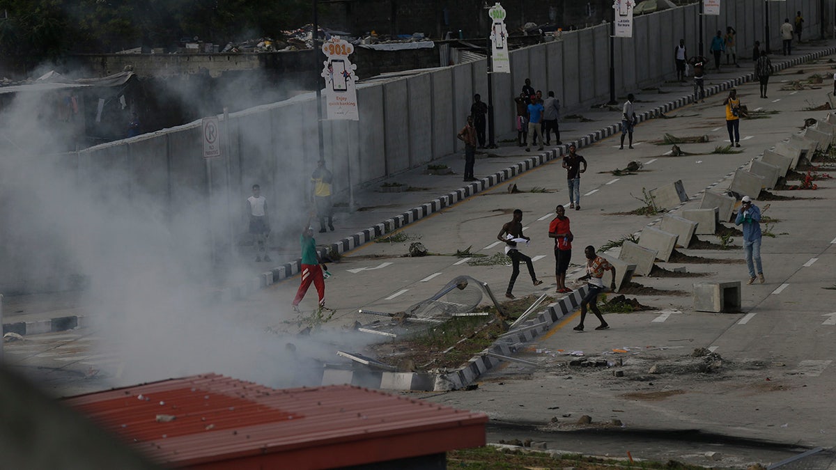 Protesters run away as police officers use teargas to disperse people demonstrating against police brutality in Lagos, Nigeria, Wednesday Oct. 21, 2020. After 13 days of protests against alleged police brutality, authorities have imposed a 24-hour curfew in Lagos, Nigeria's largest city, as moves are made to stop growing violence. ( AP Photo/Sunday Alamba)