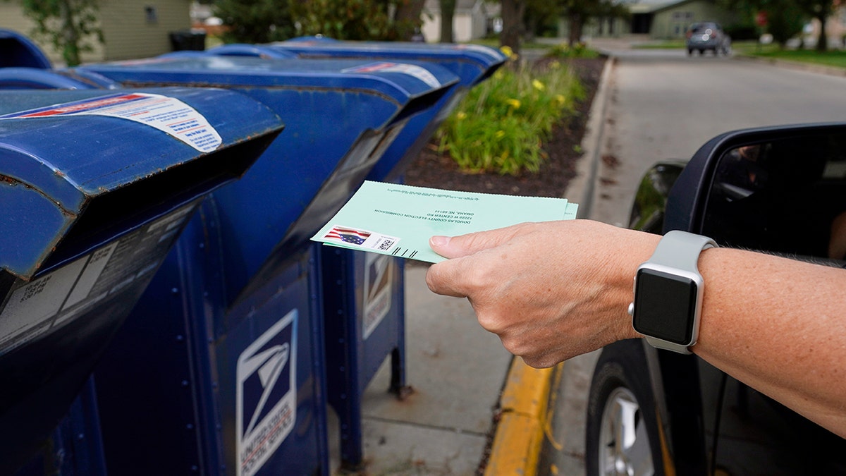 A person drops applications for mail-in-ballots into a mailbox in Omaha, Neb.  (AP Photo/Nati Harnik, File)
