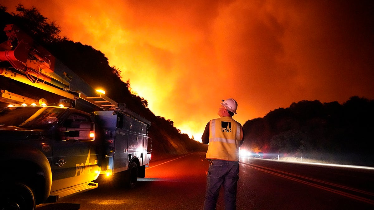 In this Tuesday, Sept. 8, 2020 file photo, A Pacific Gas and Electric worker looks up at the advancing Creek Fire along Highway 168 near Alder Springs, Calif. Pacific Gas & Electric will cut power to over 1 million people on Sunday to prevent the chance of sparking wildfires as extreme fire weather returns to the region, the utility announced Friday. Oct. 23, 2020. (AP Photo/Marcio Jose Sanchez, File)