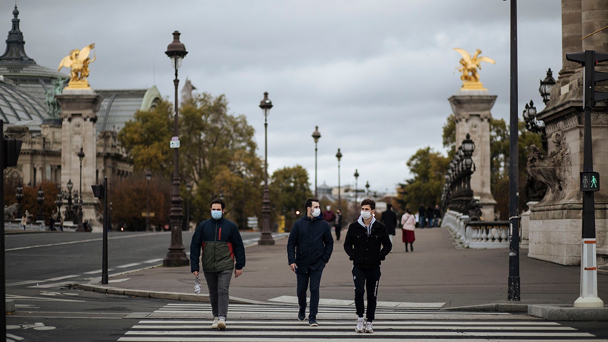 People wearing masks, walk in the Invalides district of Paris, Sunday, Oct.25, 2020. (AP Photo/Lewis Joly)