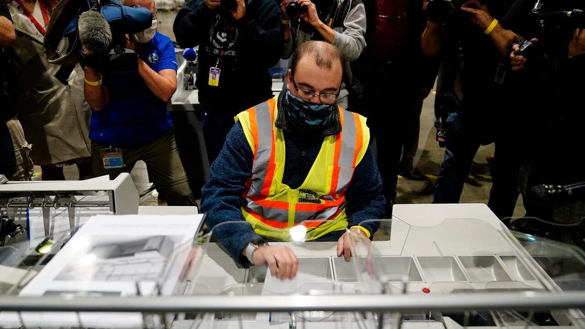John Hansberry, with the Philadelphia City Commissioners office, demonstrates an extraction machine at the city's mail-in ballot sorting and counting center in preparation for the 2020 General Election in the United States, Monday, Oct. 26, 2020, in Philadelphia. (AP Photo/Matt Slocum)