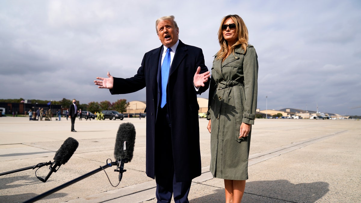 President Trump talks to reporters as first lady Melania Trump listens before boarding Air Force One for a day of campaign rallies in Michigan, Wisconsin, and Nebraska, Tuesday, Oct. 27, 2020, at Andrews Air Force Base, Md. (AP Photo/Evan Vucci)