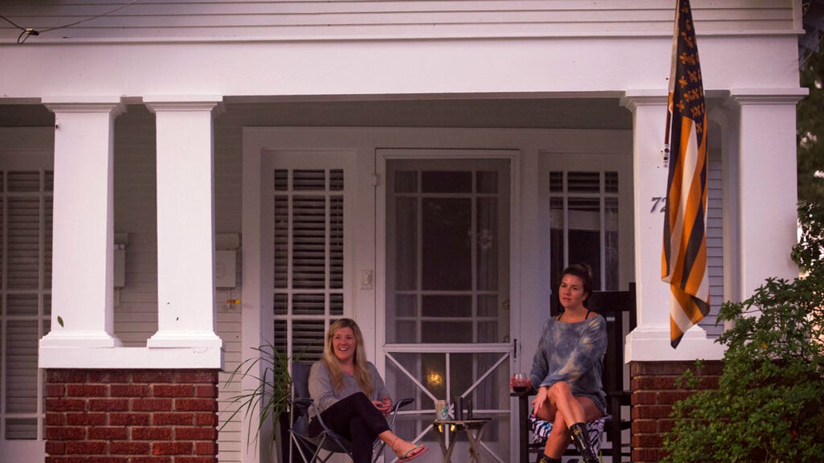 With the electricity out, people sit on the front porch of a home in New Orleans and look out at damage in the area, as Hurricane Zeta's eye wall passes near the city, Oct. 28. (Chris Granger/The Times-Picayune/The New Orleans Advocate via AP)