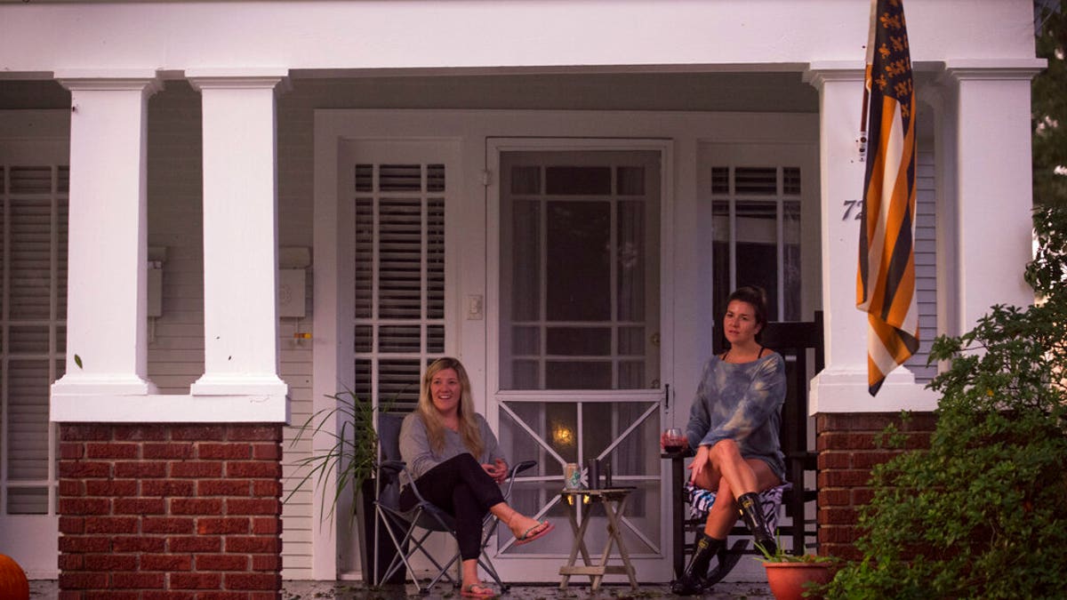 With the electricity out, people sit on the front porch of a home in New Orleans and look out at damage in the area, as Hurricane Zeta's eye wall passes near the city, Oct. 28. (Chris Granger/The Times-Picayune/The New Orleans Advocate via AP)