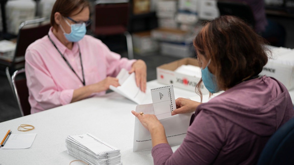 Lisa Finander, right, checks whether the voter's name is on each ballot and mailing envelope, and Laurie Mattila, left, checks whether it's correct. (GLEN STUBBE • glen.stubbe@startribune.com)