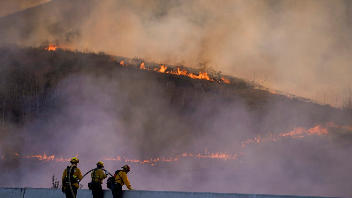 Firefighters watch as the Blue Ridge Fire burns along the 71 state highway Tuesday, Oct. 27, 2020, in Chino Hills, Calif.